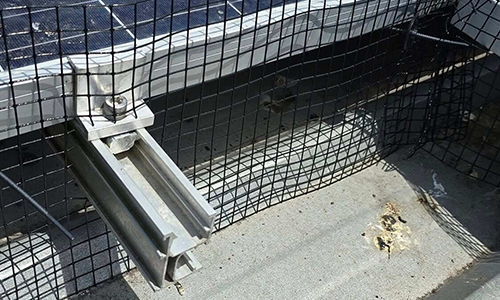 Wire mesh bird barrier fitted around solar panel mounting rails on a roof